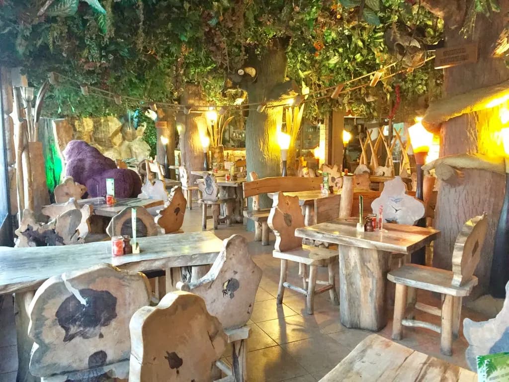 Hand-carved wooden tables and chairs under the leaf canopy in Jungle Mania's dining room